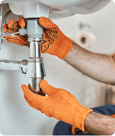 Plumber working on pipes under a sink