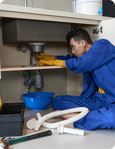 Plumber working on pipes under a sink